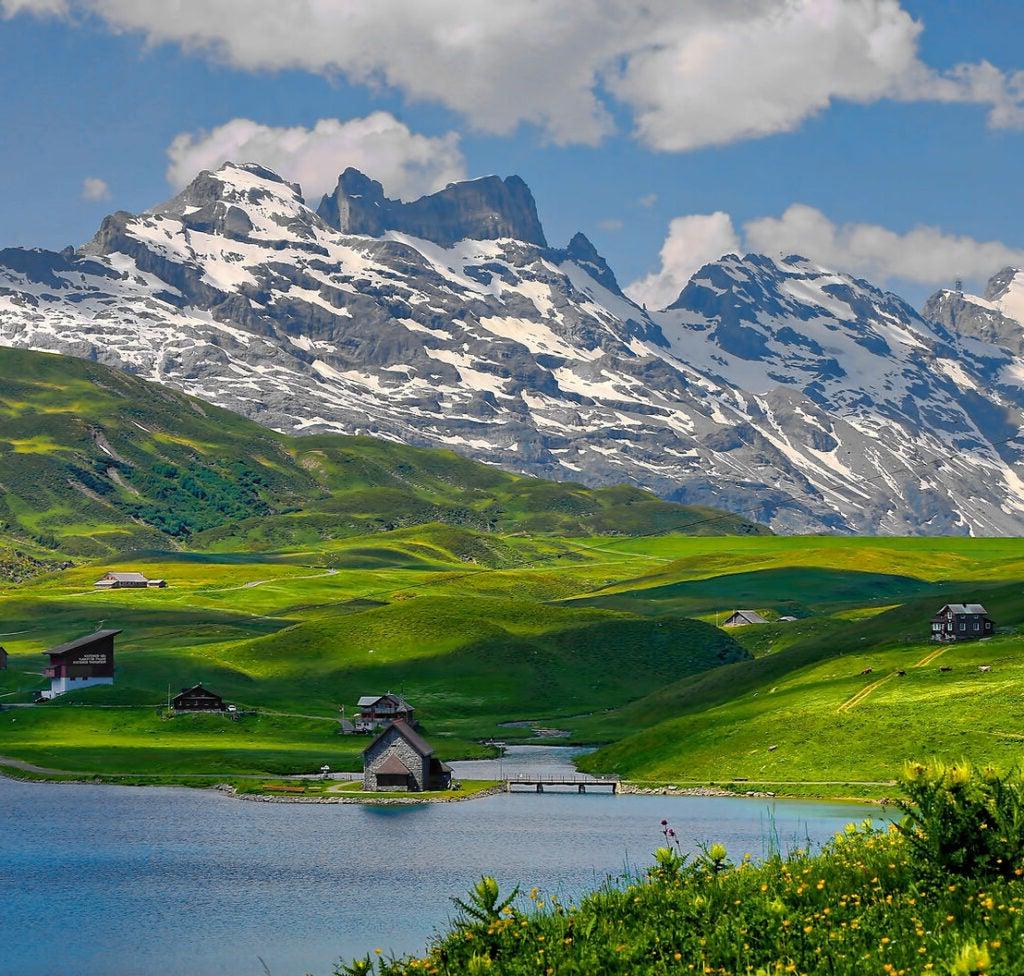 landscape of a hillside and mountain in France with a small village at the bootom of the hillside near a lake